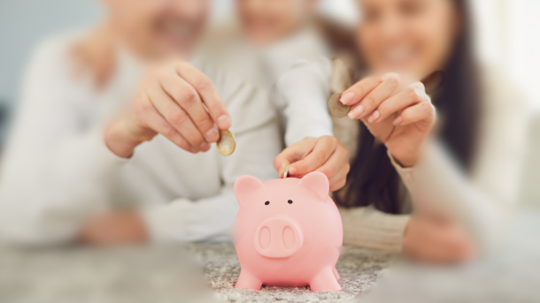Familia que pone monedas en una hucha de cerdito. El ahorro