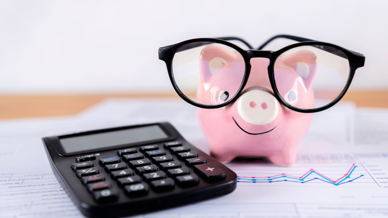 Hucha de cerdito con gafas, calculadora y muchos papeles. Definición fácil de… Presupuesto